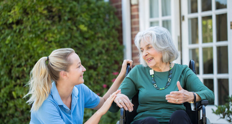 Kind female nurse looking after an elderly woman in wheelchair
